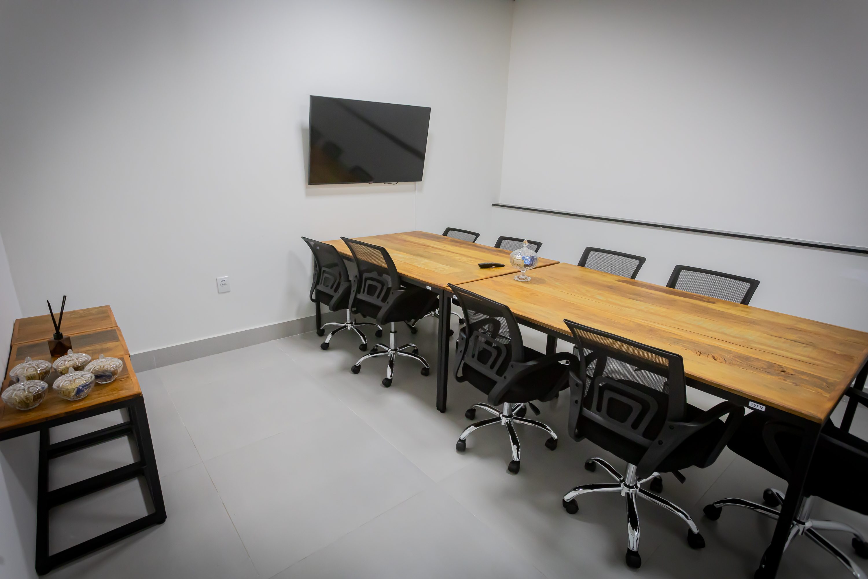 Sala de reunião equipada com TV e mesa executiva